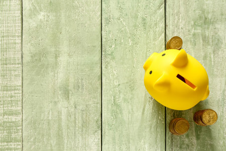 Piggy bank coins on green wooden backgroundの写真素材