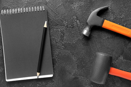 Notebook, hammer and mallet on black background. labor day celebrationの写真素材