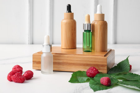 Wooden podium with bottles of cosmetic raspberry oil on white backgroundの写真素材