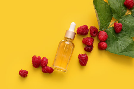 Bottle of cosmetic raspberry oil on yellow backgroundの写真素材