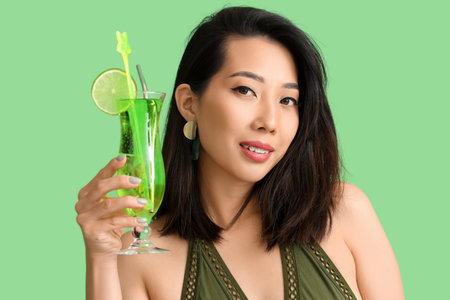 Beautiful Asian woman in swimsuit and with Mojito cocktail on green background