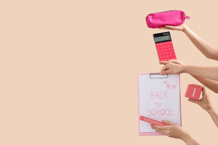 Female hands holding different stationery and notebook with text BACK TO SCHOOL on beige backgroundの写真素材