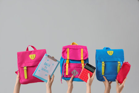 Female hands holding stationery, backpacks and notebook with text BACK TO SCHOOL on gray backgroundの写真素材