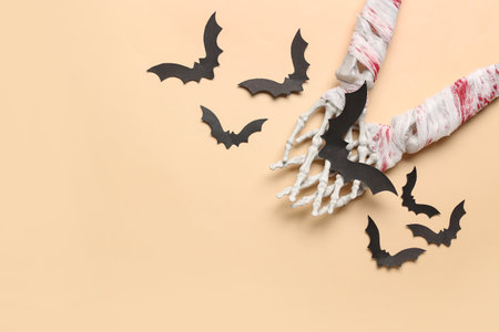Skeleton hands and paper bats for Halloween celebration on beige backgroundの写真素材