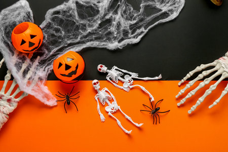 Composition with skeletons, hands, pumpkins, web and spiders for Halloween celebration on color backgroundの写真素材