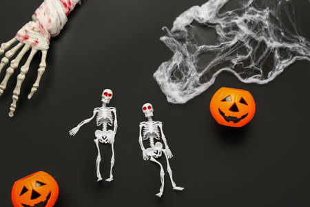 Composition with skeletons, hand, web and pumpkins for Halloween celebration on dark backgroundの写真素材