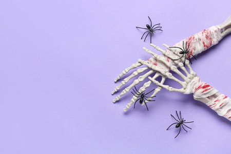 Skeleton hands with spiders for Halloween celebration on purple backgroundの写真素材