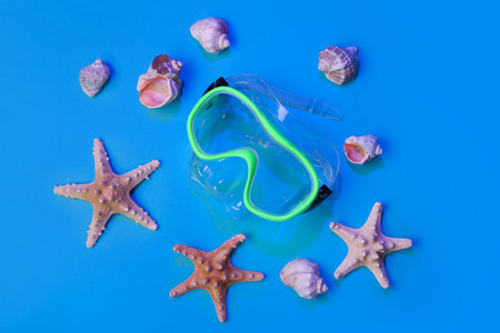 Composition with snorkeling mask, seashells and starfishes on color backgroundの写真素材