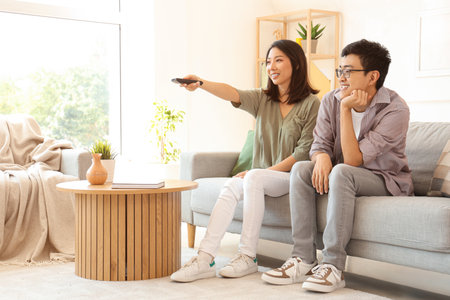 Young Asian friends watching TV at homeの写真素材