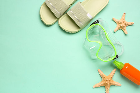 Swimming mask, flip flops and bottle of sunscreen on turquoise backgroundの写真素材
