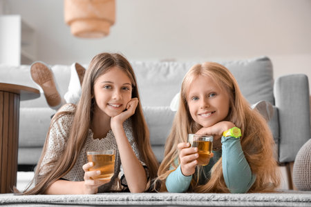 Little girls with glasses of juice at homeの写真素材
