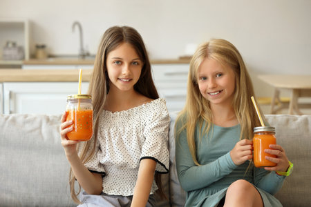 Little girls with glass jars of juice at homeの写真素材