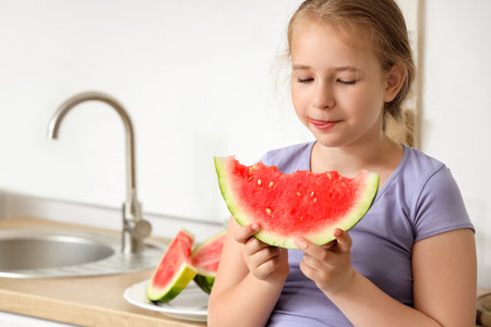Little girl with fresh watermelon in the kitchenの写真素材