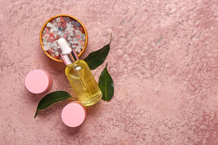 Bottle and jars of cosmetic products with sea salt on pink backgroundの写真素材