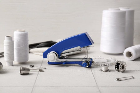 Manual sewing machine with various supplies on white tile near wall