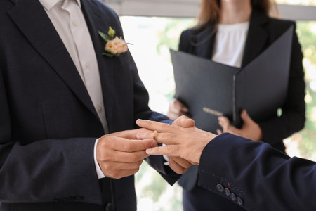 Happy gay couple putting rings at their wedding ceremony, closeupの写真素材