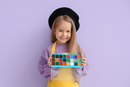 Cute little girl with paints on lilac backgroundの写真素材