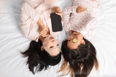 Asian mother with her little daughter taking selfie on bed, top viewの写真素材