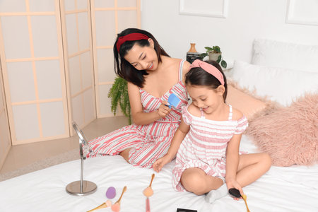 Asian mother combing her little daughter's hair in the bedroomの写真素材