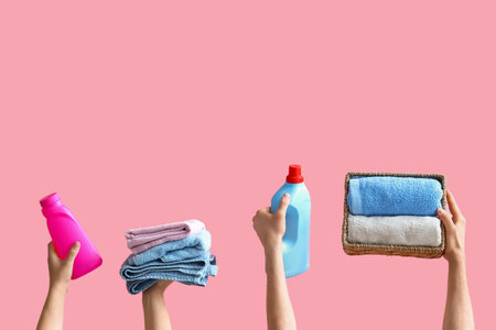 People with bottles of laundry detergent and clean towels on pink backgroundの写真素材
