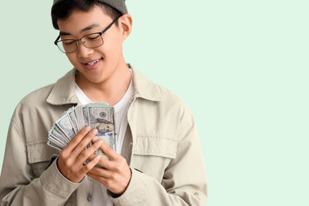 Young Asian man with dollar banknotes on green background, closeupの写真素材