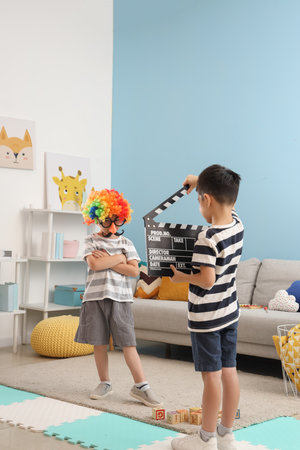 Cute little boys playing with movie clapper at homeの写真素材