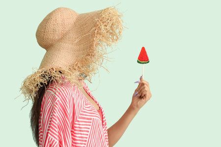Beautiful young woman with watermelon lollipop on green backgroundの写真素材