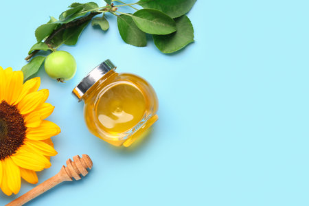 Jar of honey with apple and sunflower for Rosh Hashanah celebration (Jewish New Year) on blue backgroundの写真素材