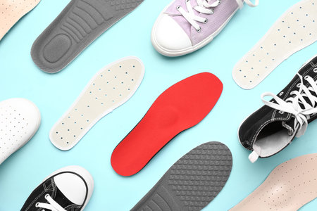 Composition with different orthopedic insoles and shoes on color background