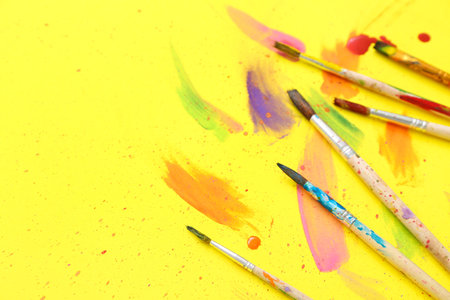 Artist's brushes with paints on yellow backgroundの写真素材