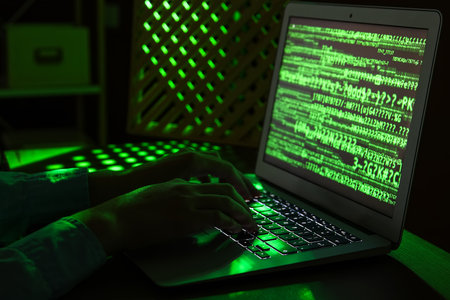 Female programmer typing on laptop keyboard at night in office, closeupの写真素材
