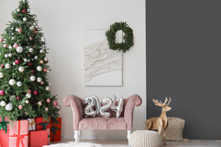Balloons in shape of figure 2024 on cozy armchair in living room with Christmas decorの写真素材