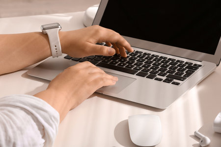 Female programmer typing on laptop keyboard at her workplace in office, closeup
