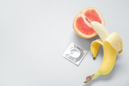 Fresh banana with grapefruit and condom on light background. sex education conceptの写真素材