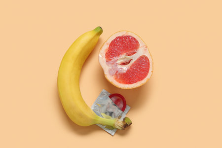 Fresh banana with grapefruit and condom on beige background. sex education conceptの写真素材