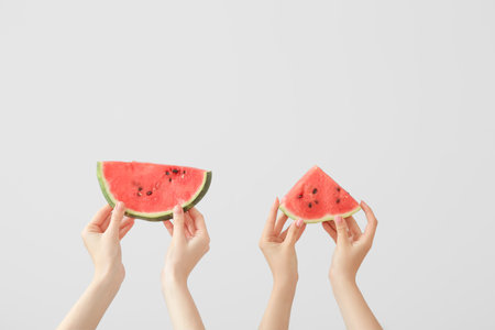 Female hands with pieces of ripe watermelon on white backgroundの写真素材