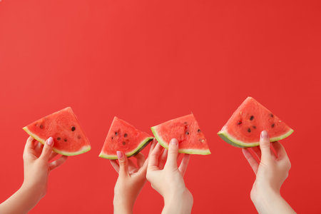 Female hands with pieces of ripe watermelon on red backgroundの写真素材