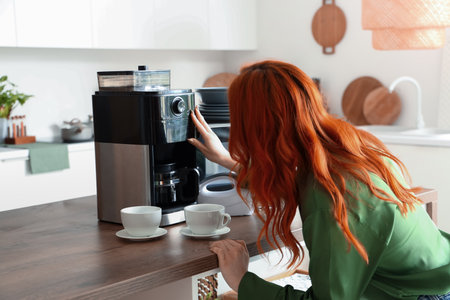 Redhead woman preparing coffee in kitchen at homeの写真素材