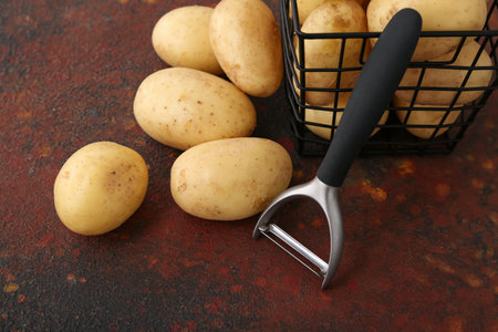 Basket with raw potatoes on dark backgroundの写真素材