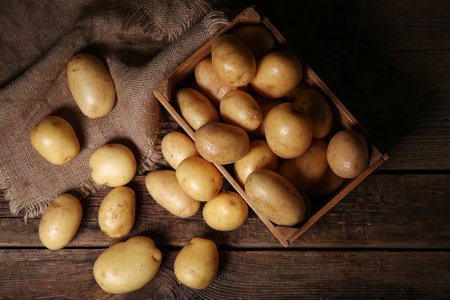 Box with raw potatoes on wooden tableの写真素材