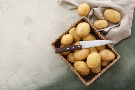 Wicker box with raw potatoes on white backgroundの写真素材