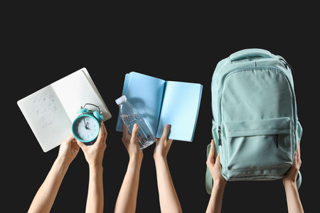 Female hands holding stationery, backpack and notebooks with text BACK TO SCHOOL on black backgroundの写真素材