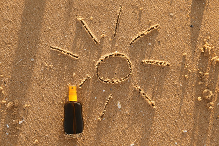 Creative composition with bottle of sunscreen cream on sand at sea beach