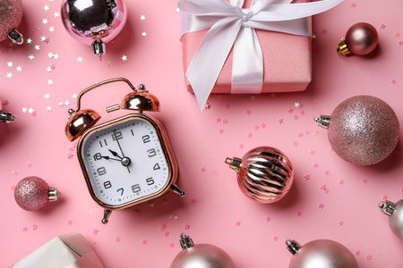 Alarm clock with Christmas decor on pink backgroundの写真素材