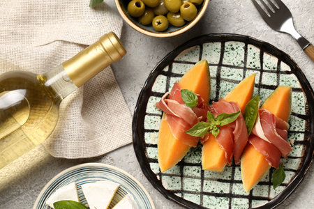 Plate with tasty melon, prosciutto and bottle of wine on grunge background, closeupの写真素材