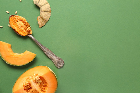 Pieces of sweet melon and spoon with seeds on green backgroundの写真素材