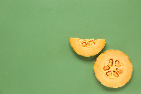 Pieces of sweet melon on green background