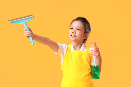Cute little janitor with squeegee and detergent on yellow backgroundの写真素材
