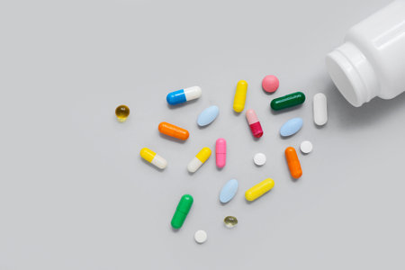 Overturned jar with different pills on gray backgroundの写真素材