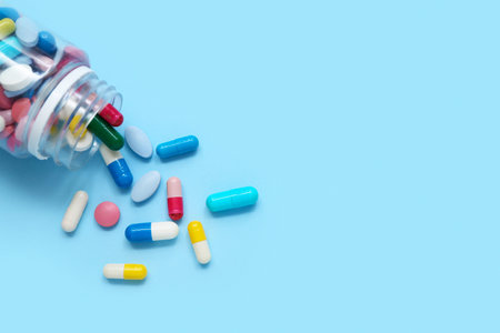 Overturned bottle with different pills on color background